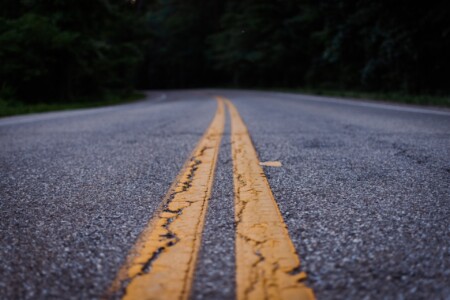 image of asphalt roadway with double yellow lines painted on it, running into the distance