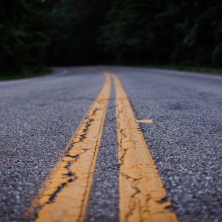 image of asphalt roadway with double yellow lines painted on it, running into the distance